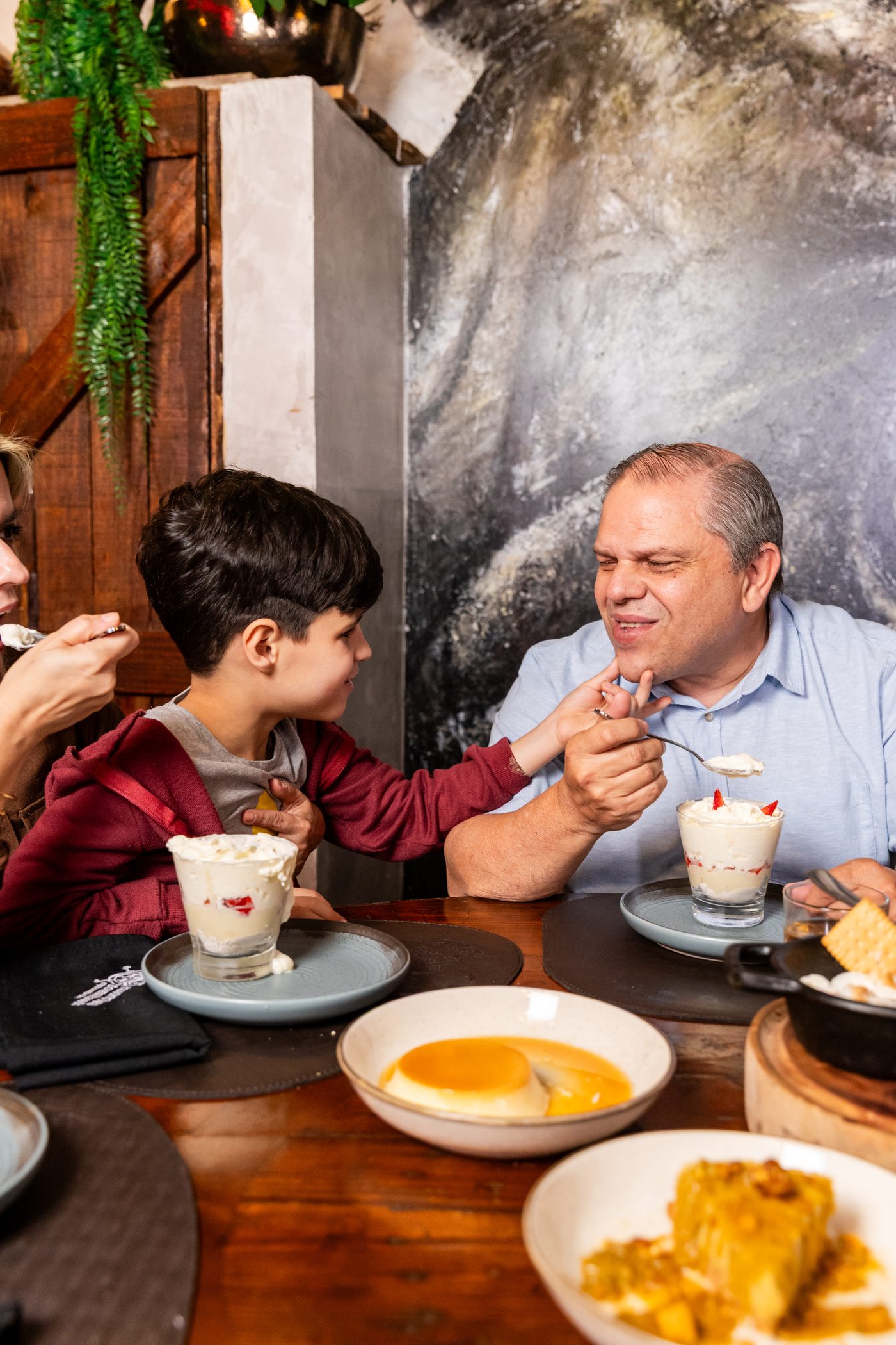 Família compartilhando sobremesas: taças de chantilly e pudim à mesa